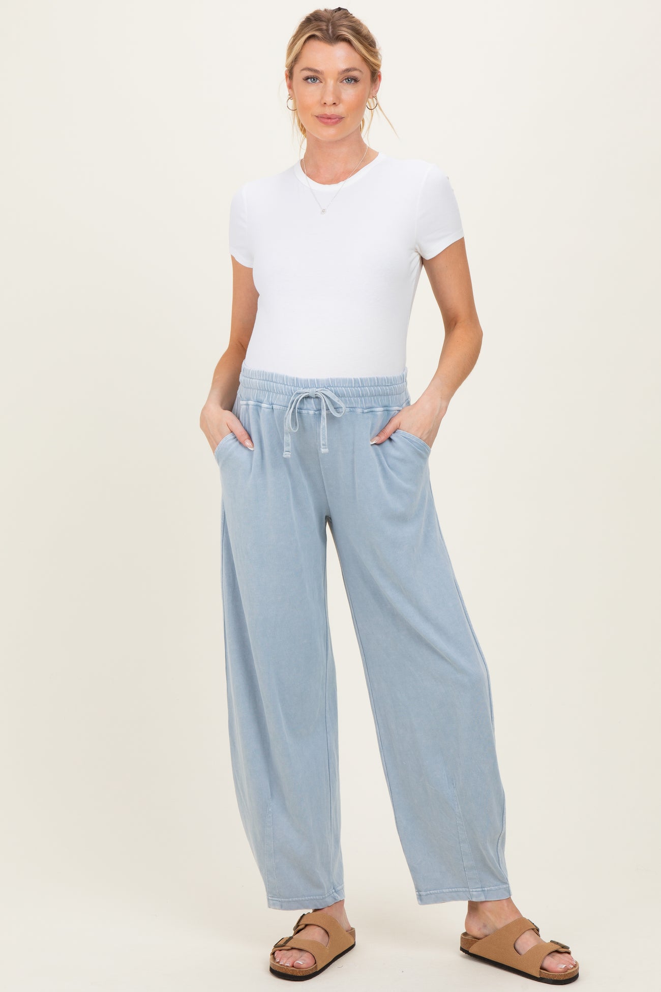 woman wearing a white short sleeve top and light blue maternity jogger pants with pockets
