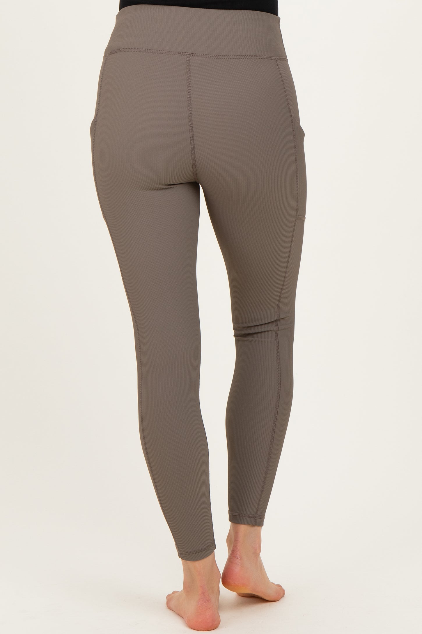 woman wearing maternity active leggings in taupe with a stretchy high waistband and side pockets, viewed from the back