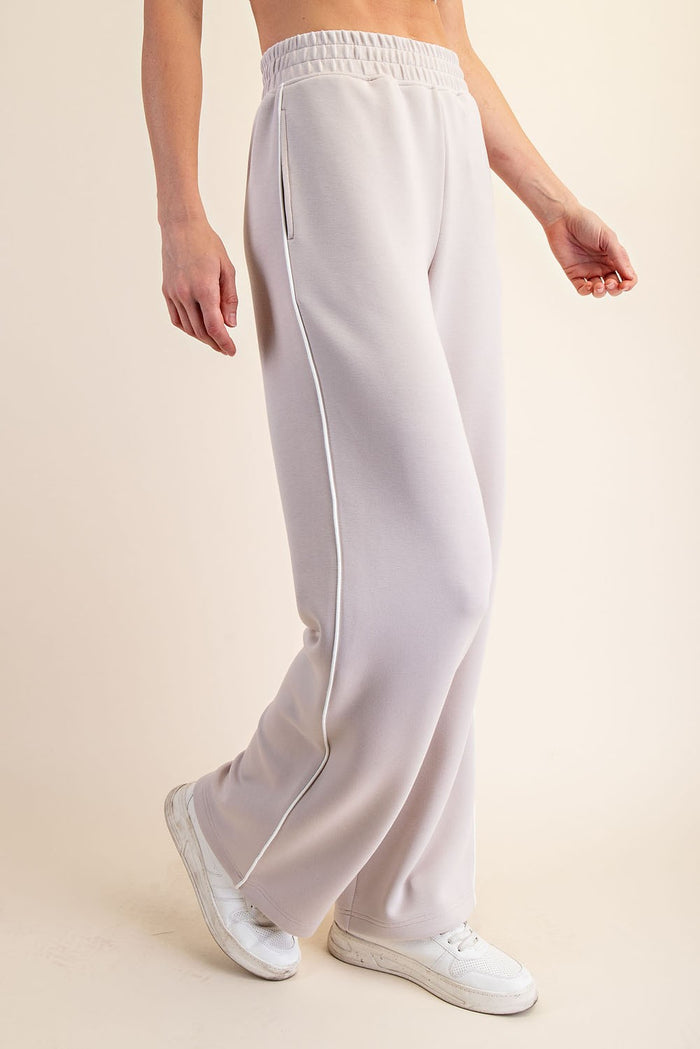 woman wearing light gray wide-leg sweatpants with side pockets and a drawstring waist, paired with white sneakers