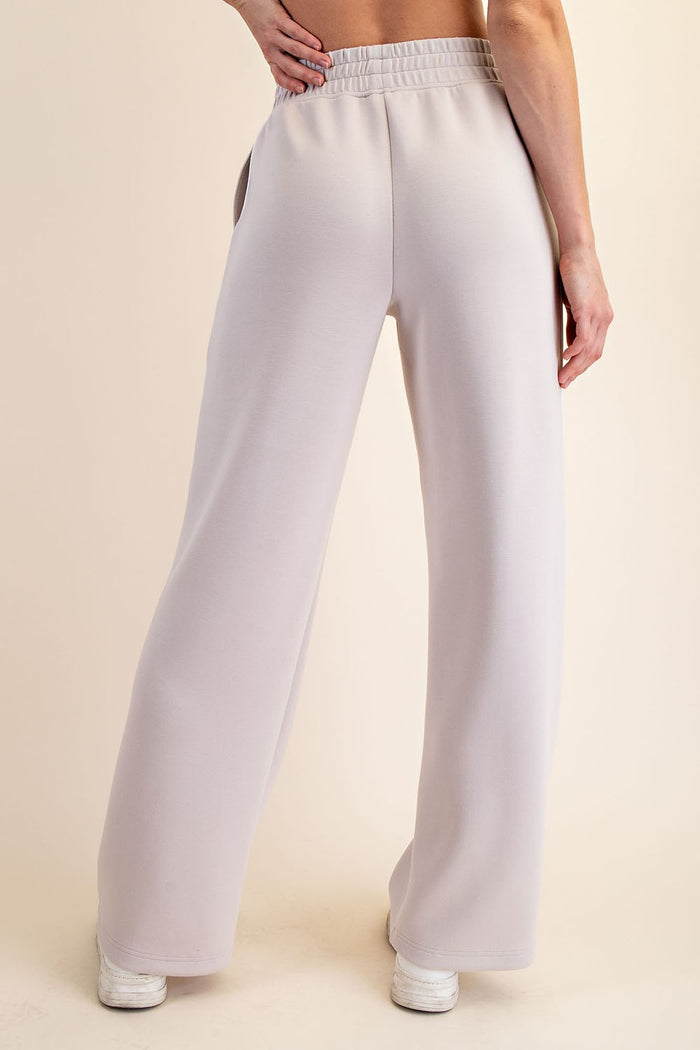 woman wearing light grey wide-leg sweatpants with an elastic waistband, shown from the back