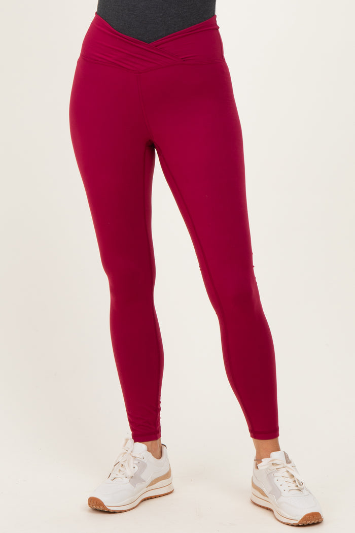 woman wearing fuchsia high-waisted active leggings with a crossover waistband and white sneakers