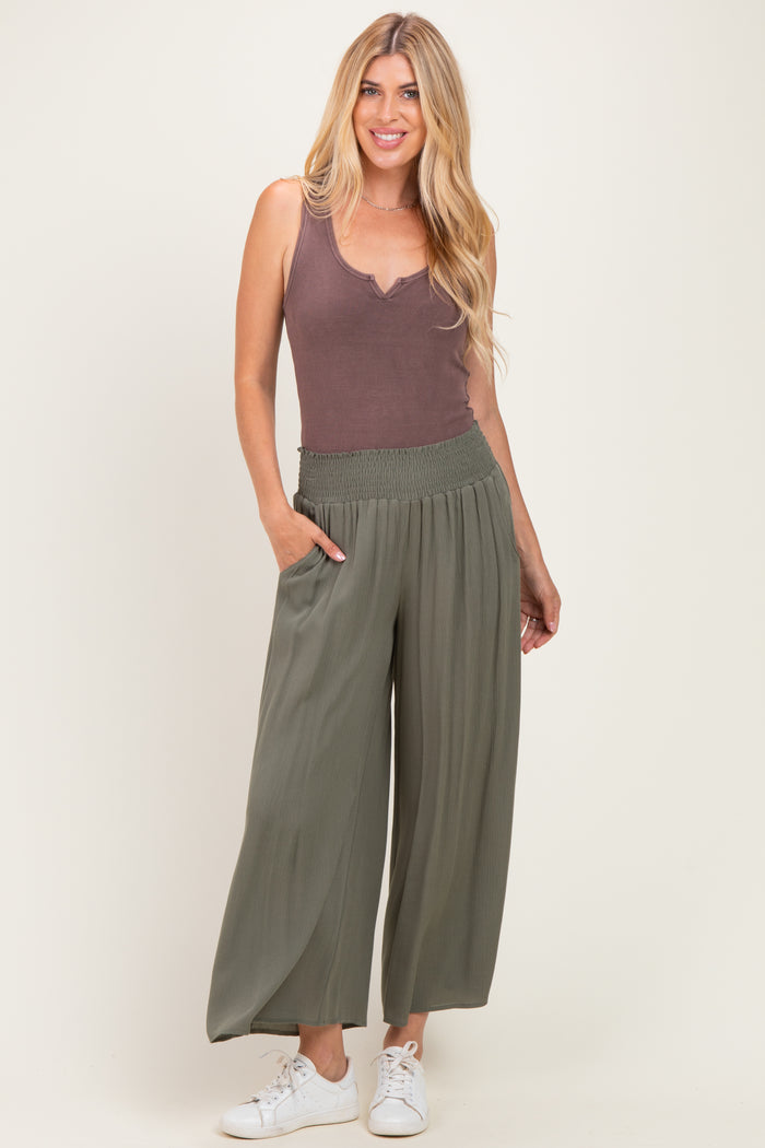 woman wearing a brown ribbed tank top and green wide-leg pants with an elastic waistband, posing with one hand in her pocket