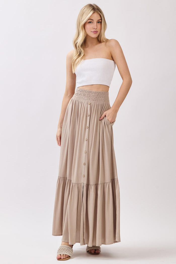 woman wearing a white strapless top and a beige maxi skirt with buttons and a smocked waist