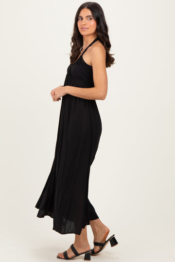 woman wearing a black maxi dress with thin straps and a flowing silhouette, styled with heeled sandals