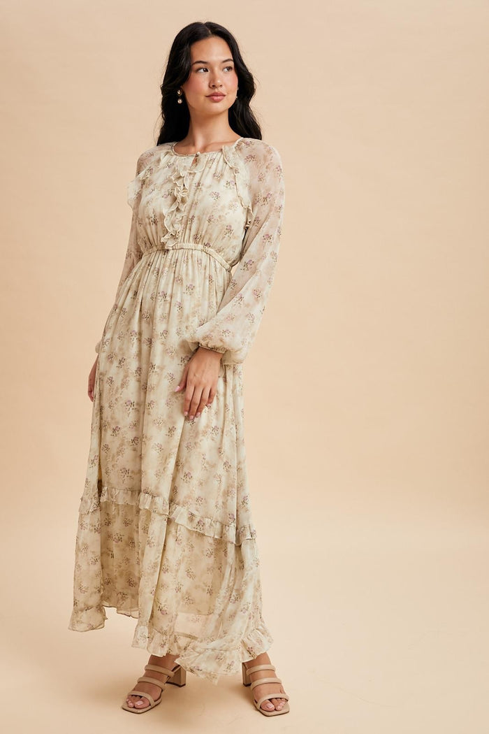 woman wearing a long sleeve floral maxi dress with a ruffled neckline and tiered skirt on a neutral background