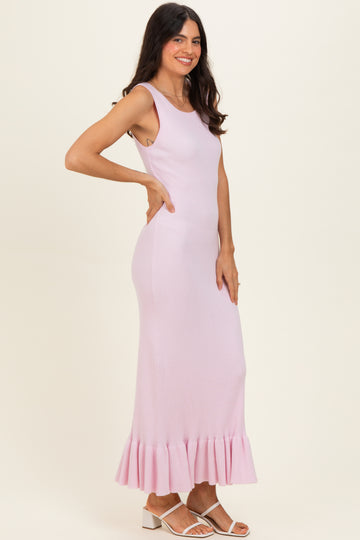 woman wearing a light pink ribbed maxi dress with a flared hem and sleeveless design
