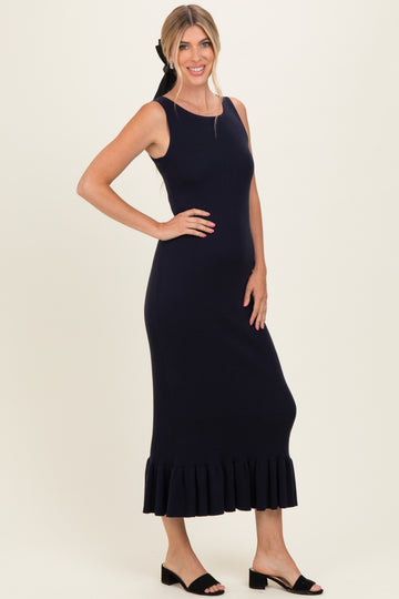 woman wearing a navy ribbed knit midi dress with a ruffle hem and smiling at the camera