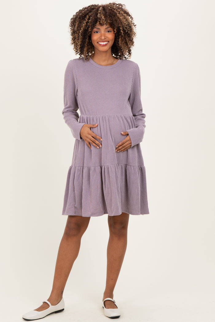 woman wearing a purple striped maternity dress with long sleeves and a tiered skirt, holding her baby bump