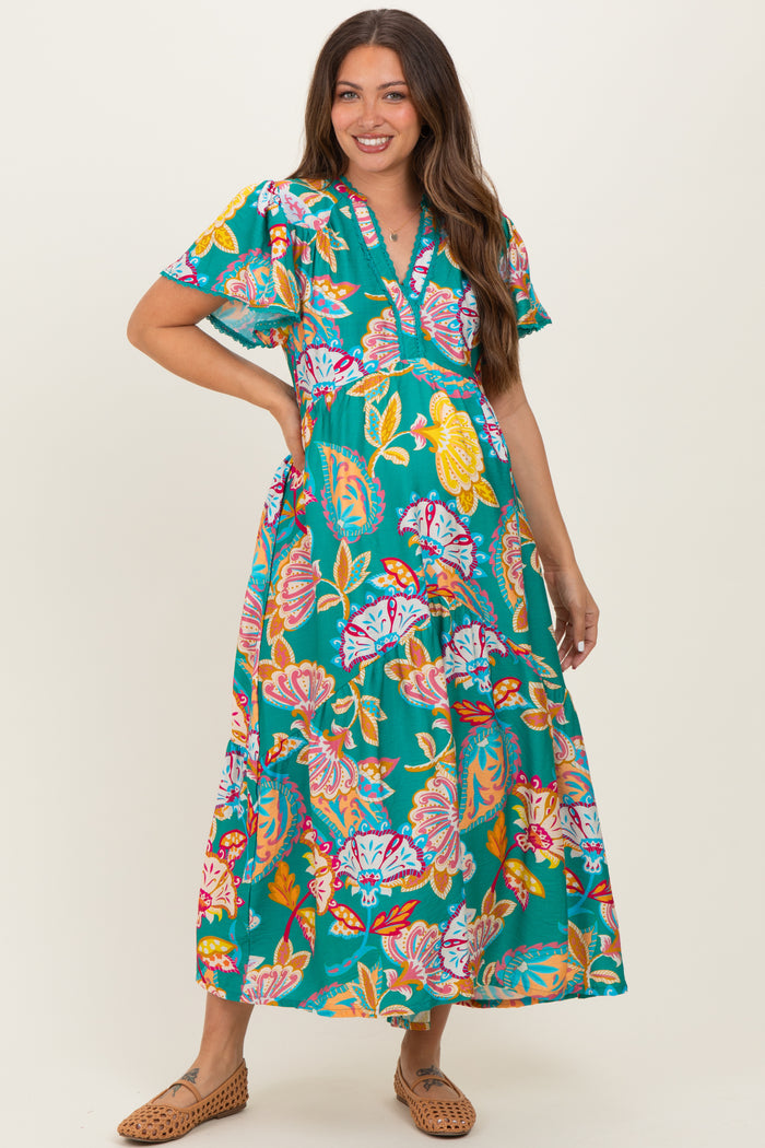 woman wearing a vibrant floral maternity maxi dress with short sleeves and a v-neckline, showcasing her baby bump