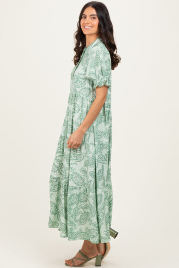 woman wearing a green floral maxi dress with short sleeves and a tiered design