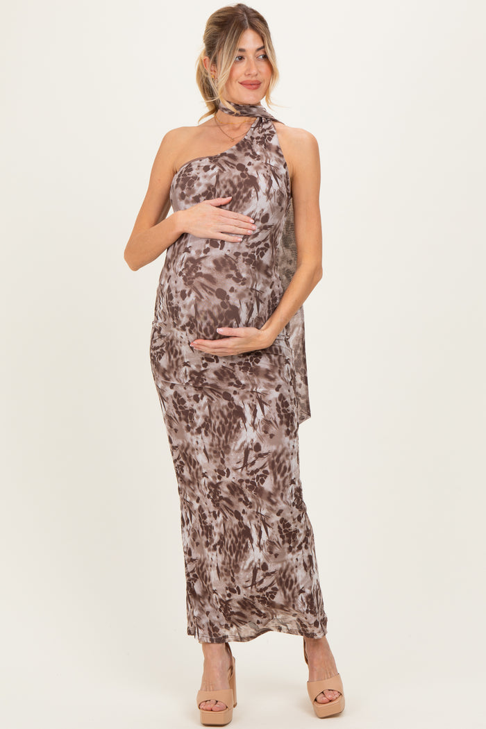 woman wearing a brown and cream floral print maternity dress with a halter neck, holding her baby bump