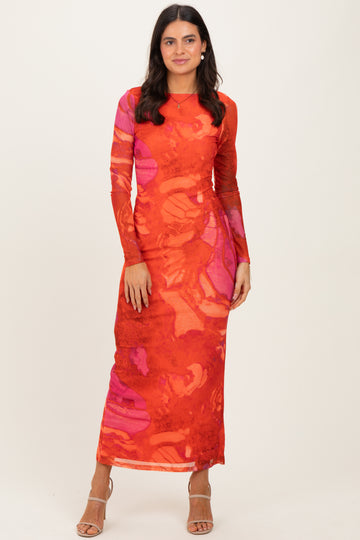 woman wearing a long sleeve red maxi dress with abstract orange and pink patterns