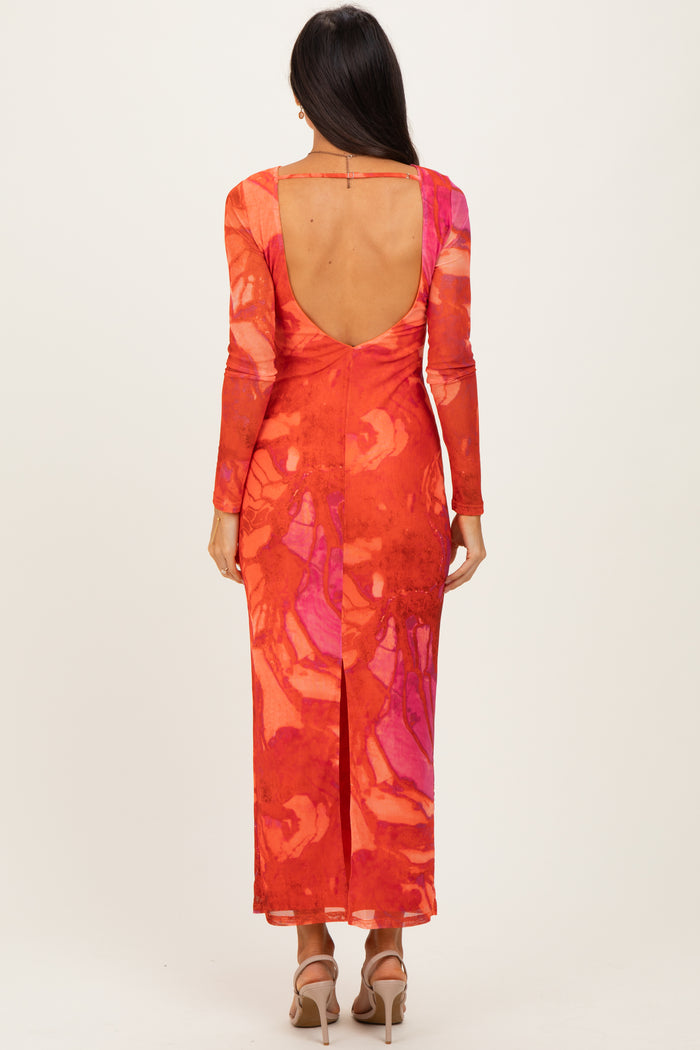 woman wearing a vibrant orange and pink long sleeve maxi dress with a deep back and side slit