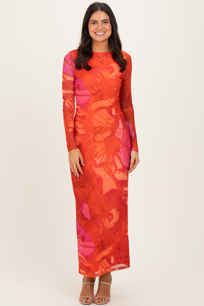 woman wearing a long sleeve red and pink abstract print maxi dress with a fitted silhouette and side slit