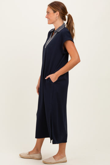 woman wearing a navy blue sleeveless maxi dress with a collared neckline and side pockets