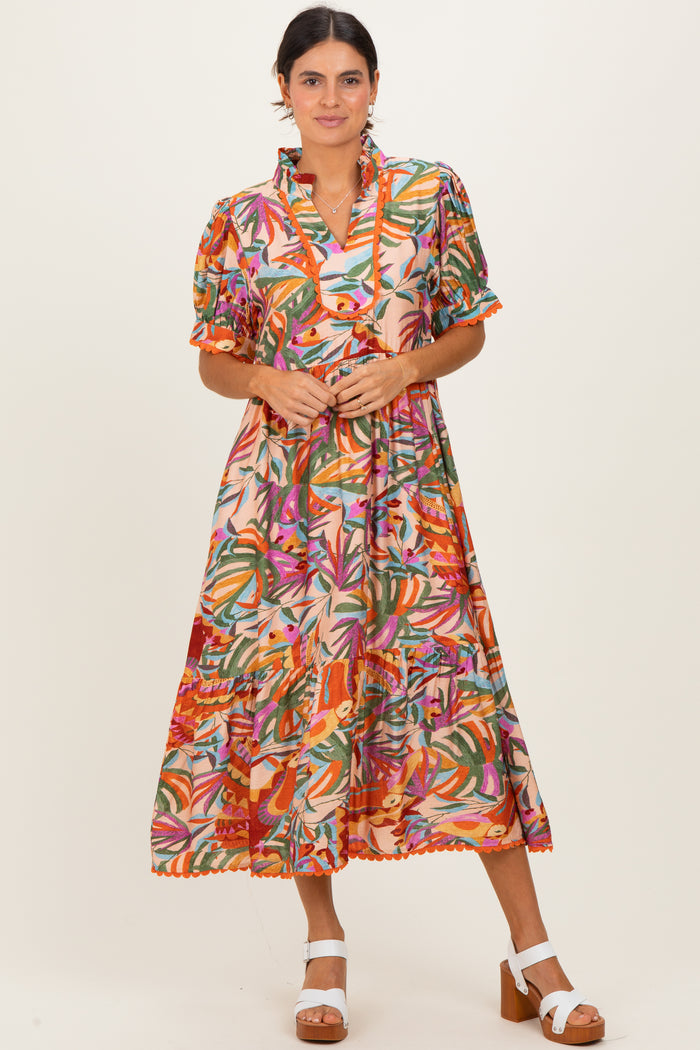 woman wearing a colorful floral print midi dress with short sleeves and a ruffled collar, standing and smiling