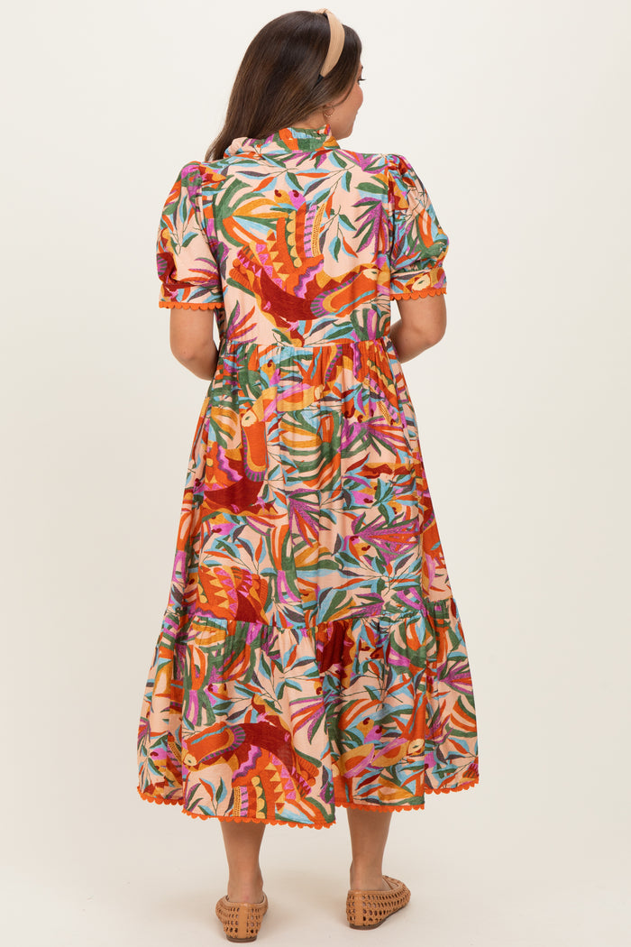 woman wearing a colorful floral print maternity maxi dress with puff sleeves and a tiered skirt from the back