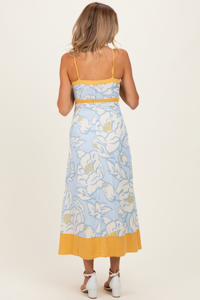 woman wearing a blue floral maternity maxi dress with yellow accents, showing the back view