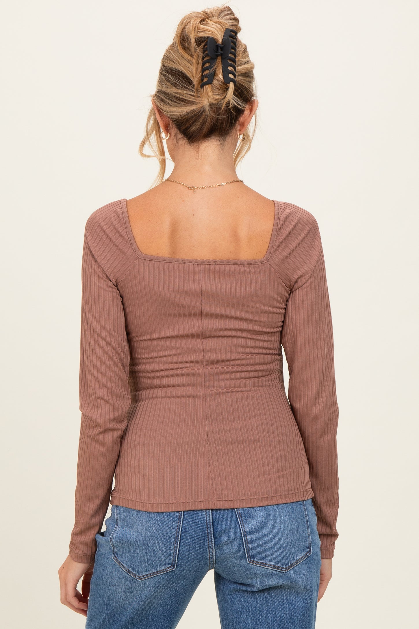 woman wearing a dusty rose long sleeve ribbed maternity top with a square neckline and gathered back details