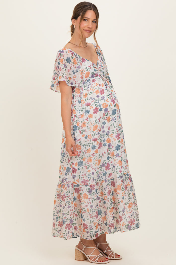 woman wearing a floral print maternity maxi dress with flutter sleeves and a visible baby bump