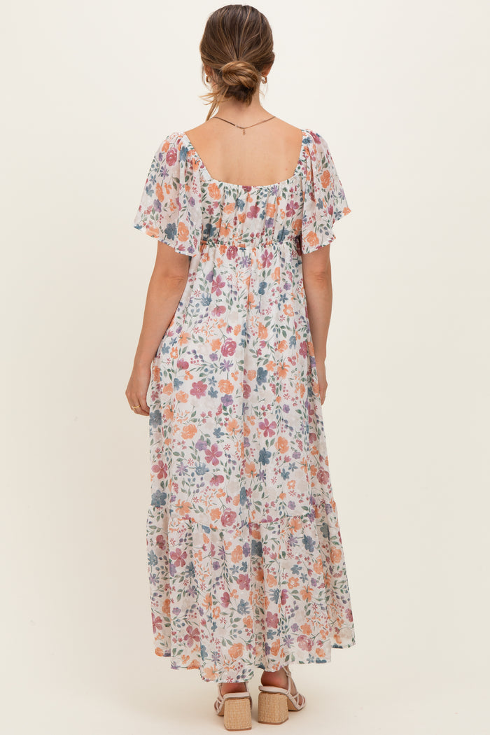 woman wearing a flowy floral maternity maxi dress with short flutter sleeves and a smocked back detail