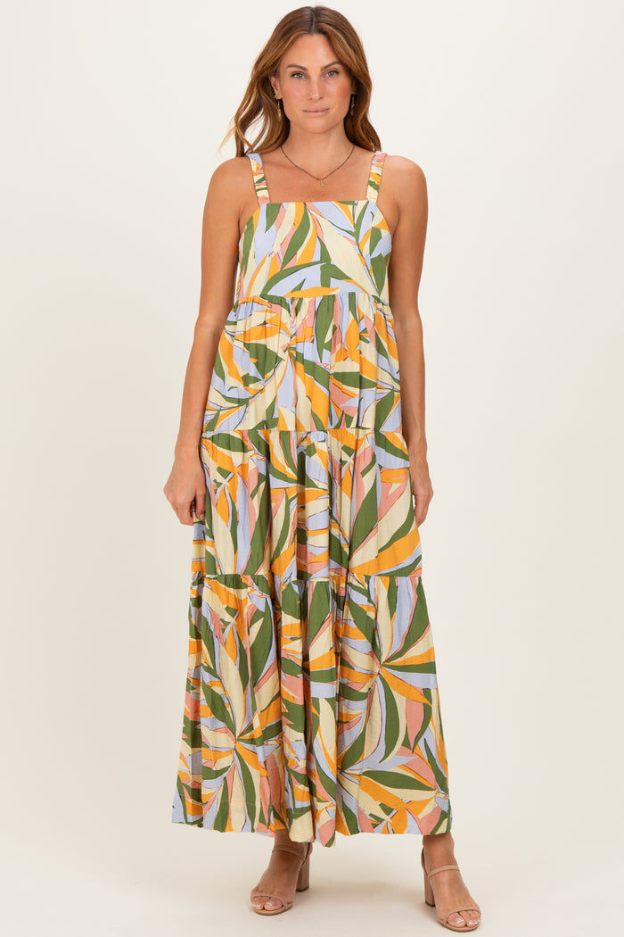 woman wearing a colorful floral print maxi dress with adjustable straps and a tiered design
