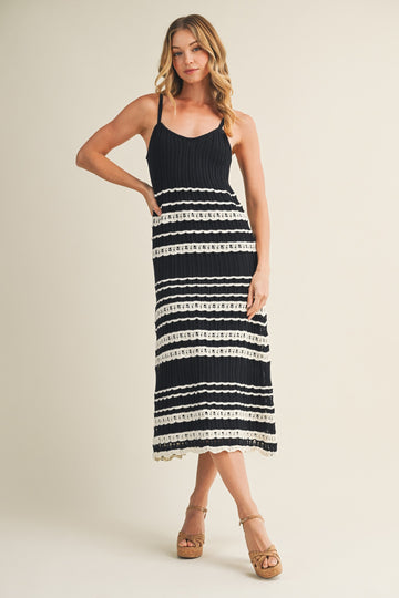 woman wearing a black and white striped knit maxi dress with spaghetti straps and lace trim details