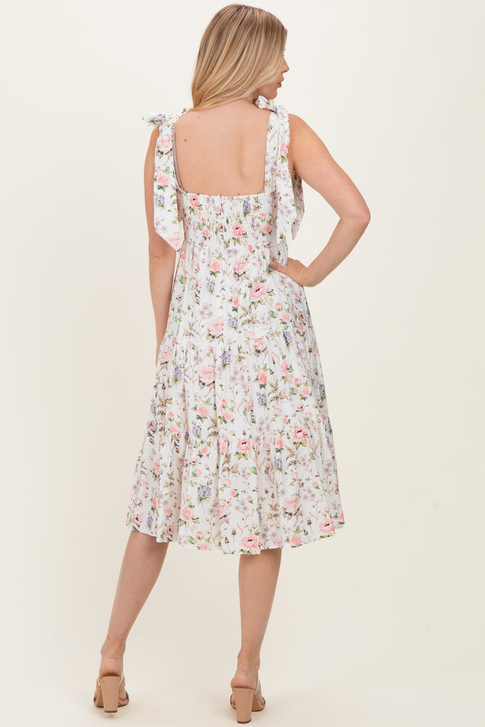 woman wearing a floral midi dress with tie shoulder straps and a smocked back, viewed from the back