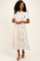 woman wearing a light floral pattern midi dress with short sleeves and a fitted waist, standing on a neutral background