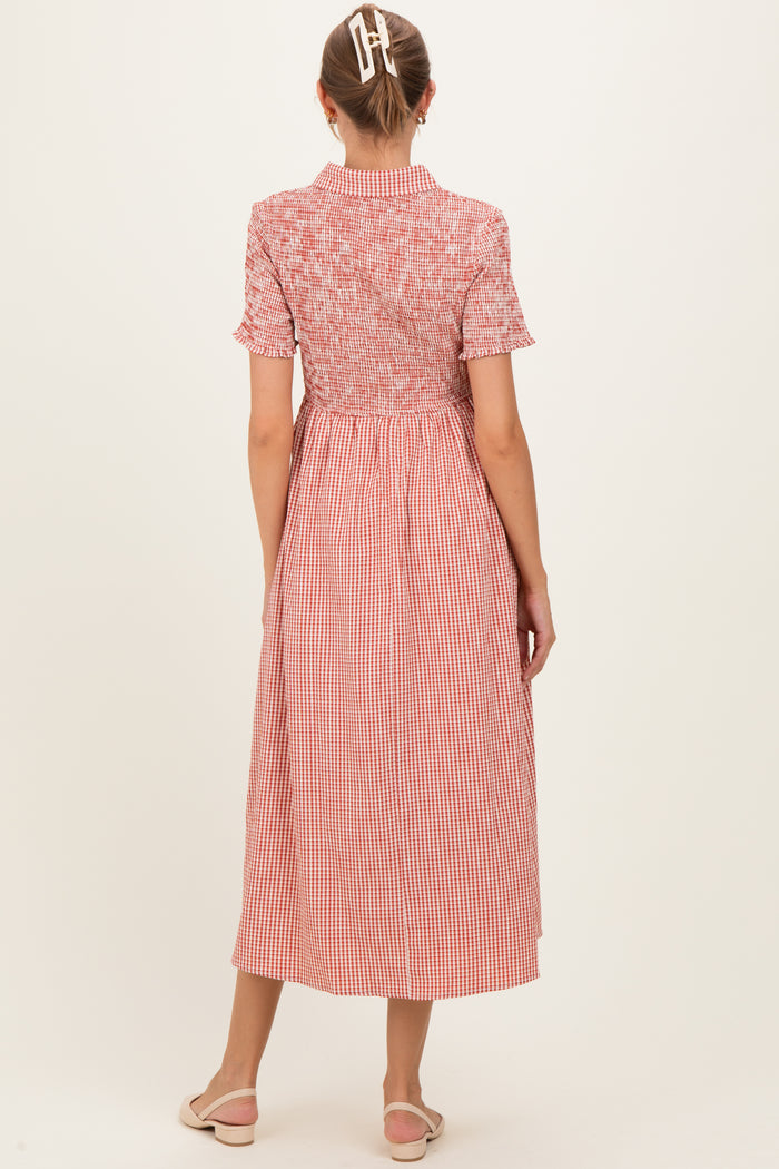 woman wearing a red and white gingham maternity dress with a smocked bodice and short sleeves, seen from the back