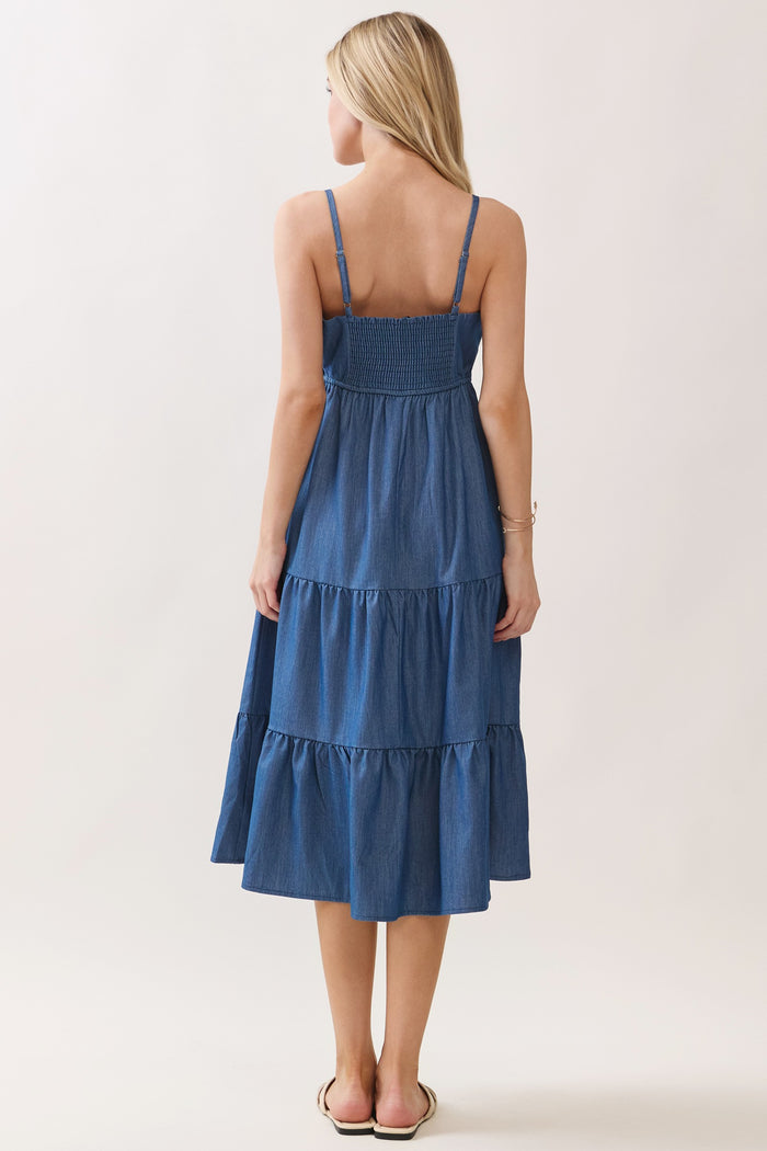 woman wearing a back view of a tiered denim maxi dress with a smocked bodice and adjustable straps
