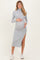 woman wearing a light grey ribbed maternity dress with a side slit, showing her baby bump, styled with white sneakers