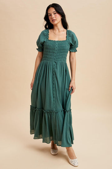 woman wearing a green smocked maxi dress with puff sleeves and button details