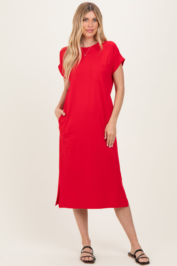 woman wearing a red short sleeve midi dress with a pocket and side slits, standing with one hand in the pocket