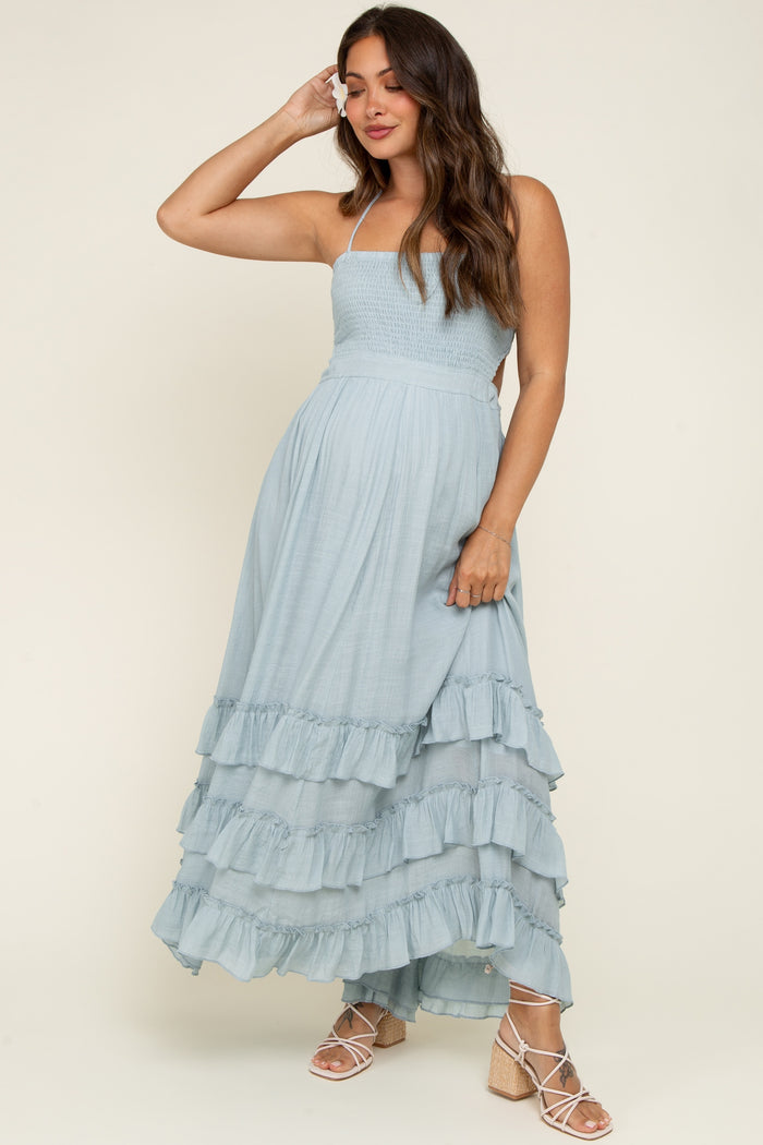 woman wearing a light blue maternity maxi dress with ruffled tiers and spaghetti straps, showing her baby bump