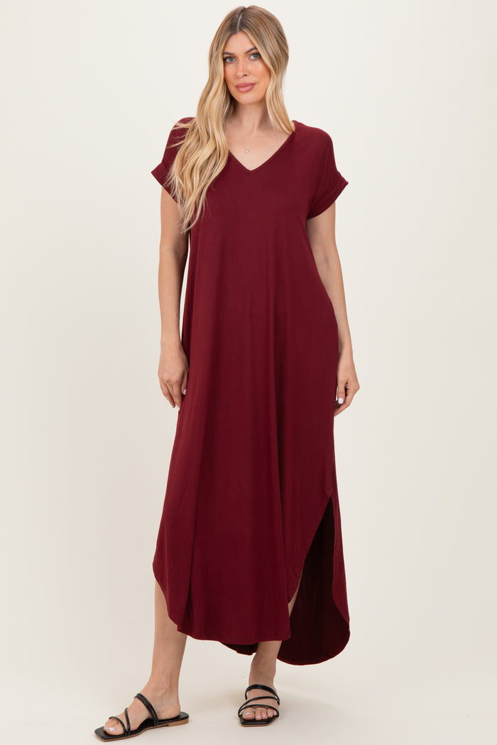 woman wearing a burgundy short sleeve maxi dress with a v-neck and side slit, styled with black sandals
