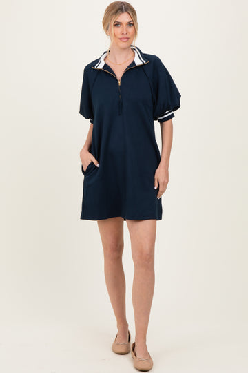 woman wearing a navy zip-up dress with a collar and short sleeves, featuring striped detailing and side pockets