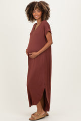 woman wearing a rust colored maternity maxi dress with a side slit and holding her baby bump