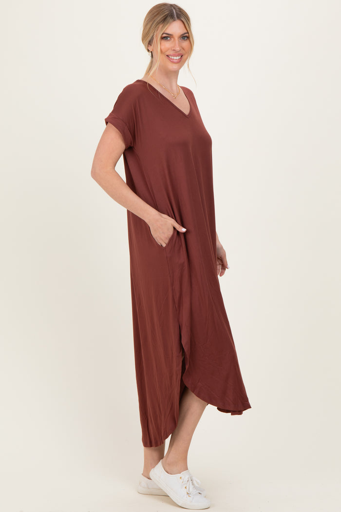 woman wearing a rust colored short sleeve maxi dress with pockets and a v-neckline