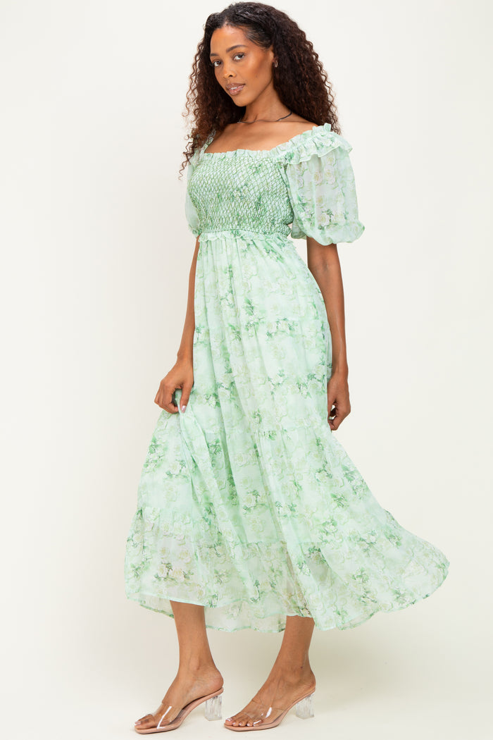 woman wearing a green floral midi dress with puff sleeves and a smocked bodice