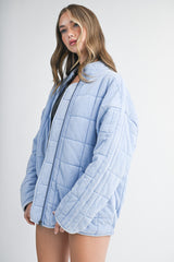 woman wearing a light blue quilted oversized jacket with a zip front and gray top underneath