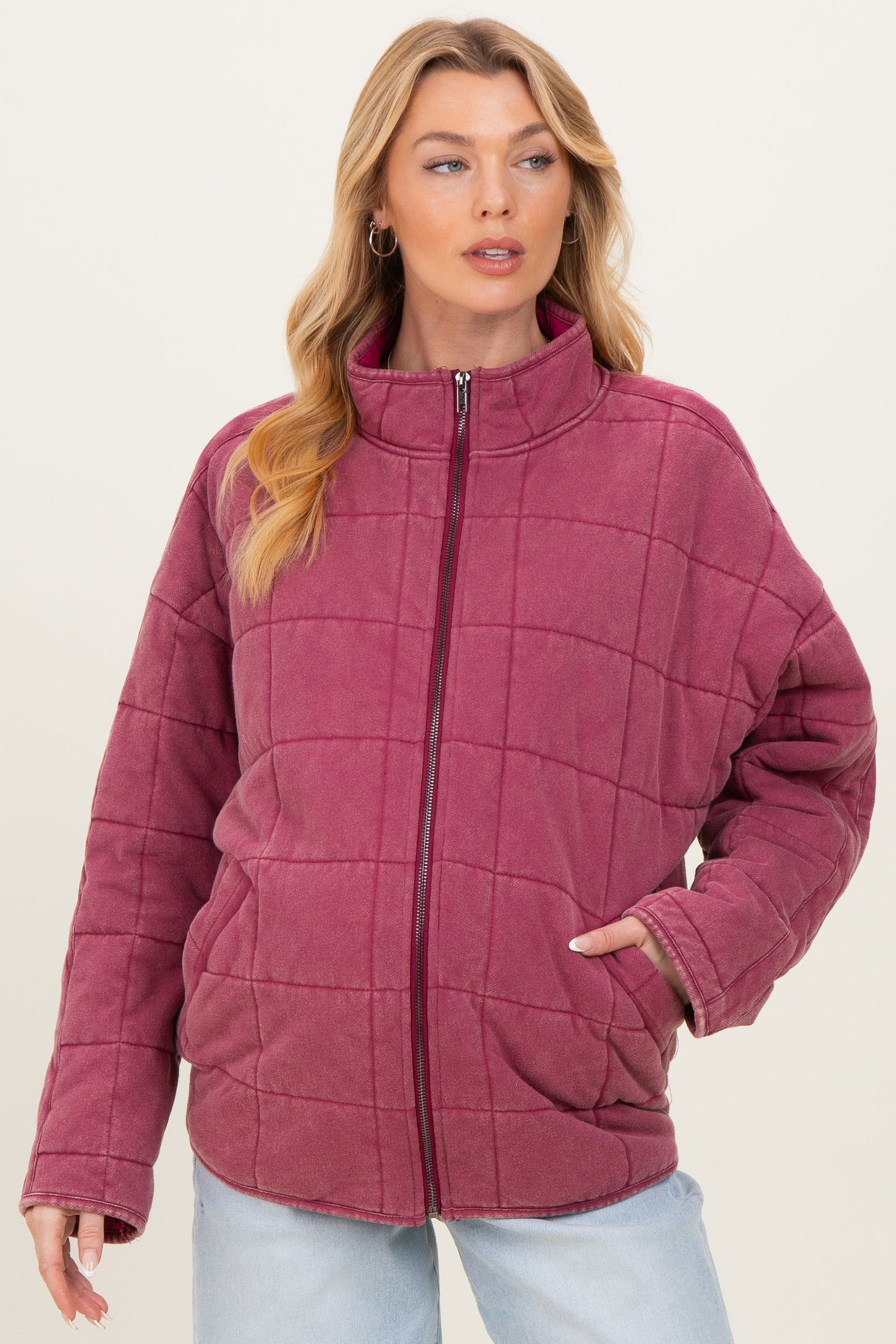 woman wearing a burgundy quilted maternity jacket with a high collar and side pockets