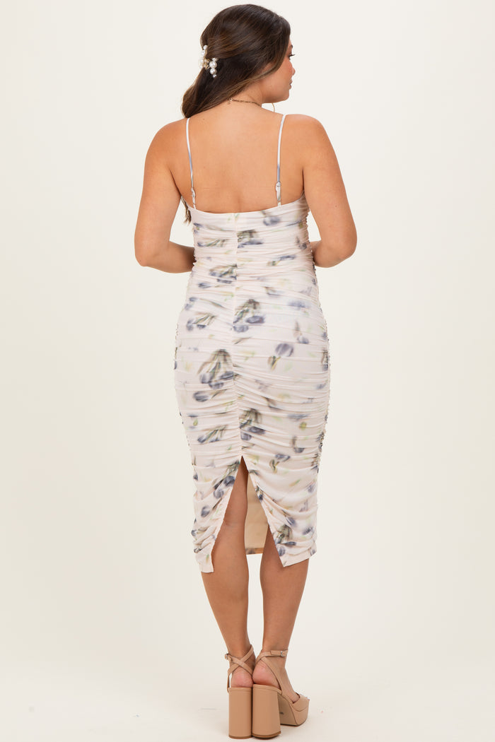 woman wearing a floral print maternity dress with adjustable straps and a fitted silhouette, showing a side slit