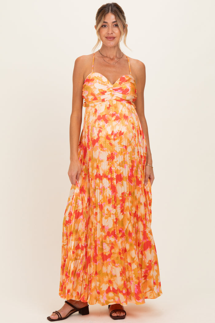 woman wearing a floral pleated maternity maxi dress with a sweetheart neckline and a visible baby bump