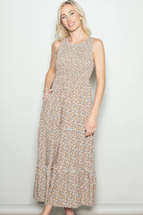 woman wearing a sleeveless floral maxi dress with a tiered hem and side pockets