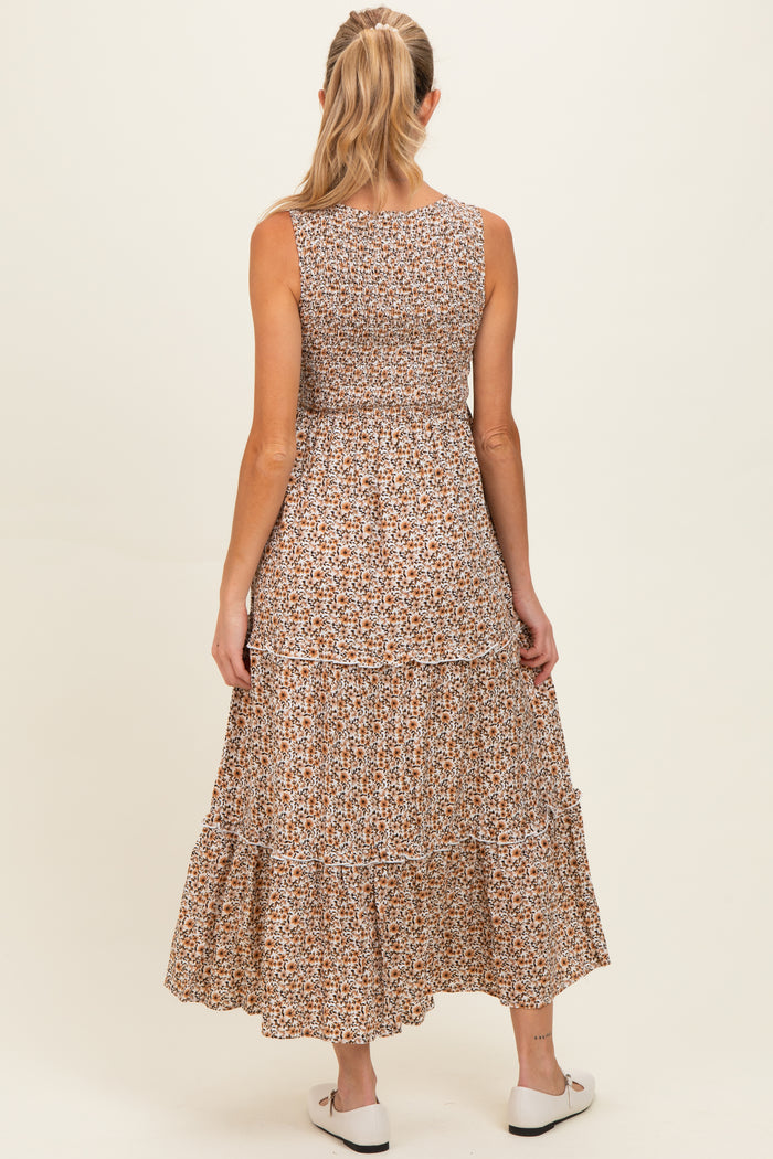 woman wearing a sleeveless brown floral maternity maxi dress with a tiered hem, seen from the back