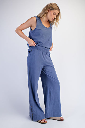 woman wearing a blue tank top and matching wide-leg pants with button details on the side