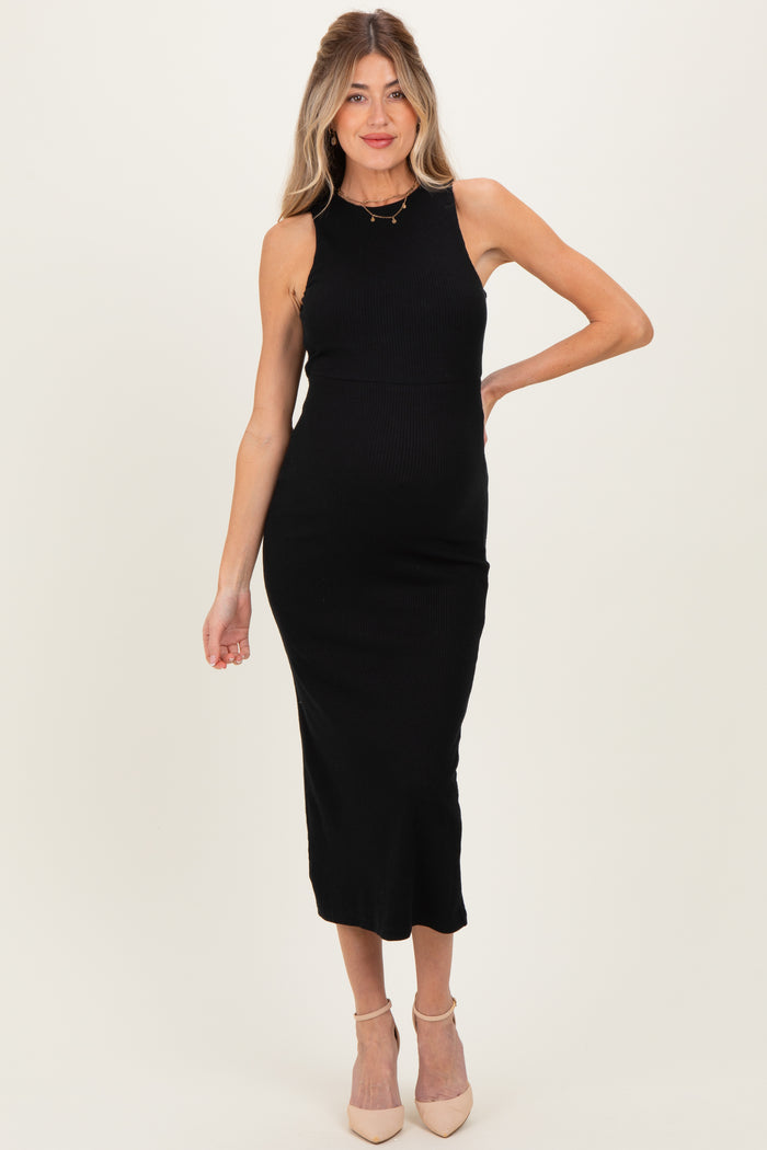 woman wearing a black ribbed midi maternity dress, posing with one hand on her hip and a visible baby bump