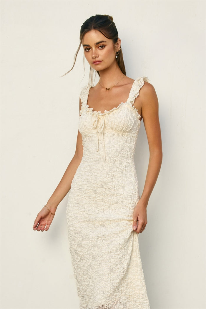 woman wearing a cream colored smocked fitted dress with ruffled straps and a square neckline