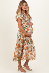 woman wearing a floral maternity dress with a fitted bodice and flowy skirt, holding her baby bump